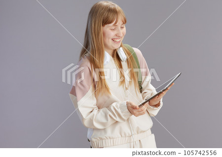happy trendy teenager girl in beige tracksuit using tablet PC happy trendy teenager girl in beige tracksuit using tablet PC 105742556
