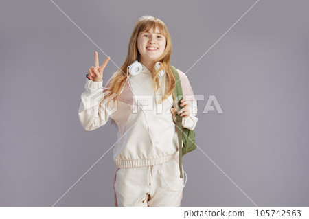 Portrait of happy trendy girl in beige tracksuit showing victory Portrait of happy trendy girl in beige tracksuit showing victory 105742563