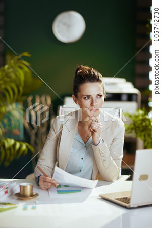 pensive modern accountant woman in modern green office 105742730