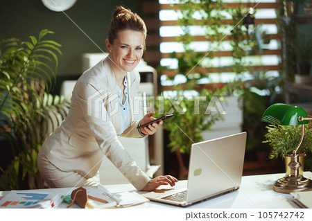 smiling bookkeeper woman in green office using phone 105742742