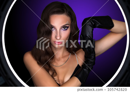 Female portrait of a young brunette girl with a beautiful evening make-up. The girl has gloves on her hands Female portrait of a young brunette girl with a beautiful evening make-up. The girl has gloves on her hands 105742820