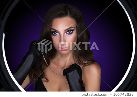 Female portrait of a young brunette girl with a beautiful evening make-up. The girl has gloves on her hands Female portrait of a young brunette girl with a beautiful evening make-up. The girl has gloves on her hands 105742822