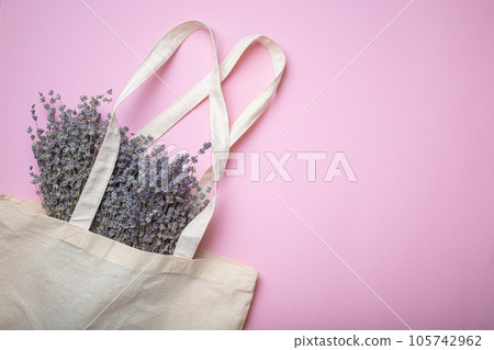 Lavender flowers bouquet in beige eco linen shopper bag on purple background top view. Romantic spring or summer girly feminine background, space for text Lavender flowers bouquet in beige eco linen shopper bag on purple background top view. Romantic spring or summer girly feminine background, space for text 105742962