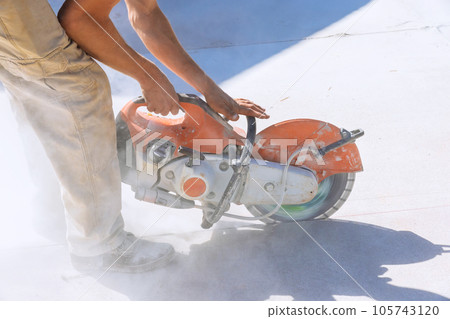 Construction worker with working diamond blade saw to cut off concrete paving sidewalk 105743120