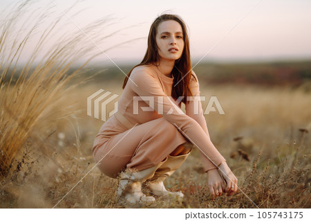 Beautiful model in stylish clothes posing on autumn field. Fashion concept. Lifestyle, recreation. 105743175
