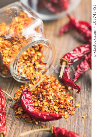 Crushed and whole chili peppers on wooden table. Crushed and whole chili peppers on wooden table. 105743453