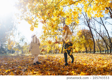 Happy mother and daughter have fun in autumn park at sunset. Family on walk. Childhood, walks, rest. Happy mother and daughter have fun in autumn park at sunset. Family on walk. Childhood, walks, rest. 105743553