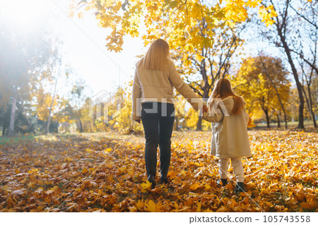 Happy mother and daughter have fun in autumn park at sunset. Family on walk. Childhood, walks, rest. Happy mother and daughter have fun in autumn park at sunset. Family on walk. Childhood, walks, rest. 105743558