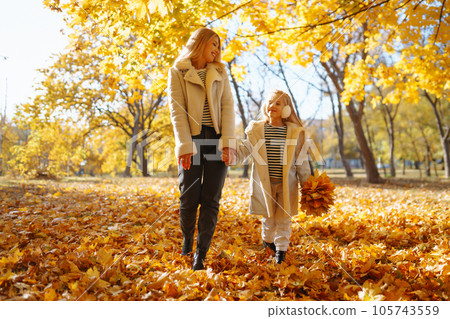 Happy mother and daughter have fun in autumn park at sunset. Family on walk. Childhood, walks, rest. Happy mother and daughter have fun in autumn park at sunset. Family on walk. Childhood, walks, rest. 105743559