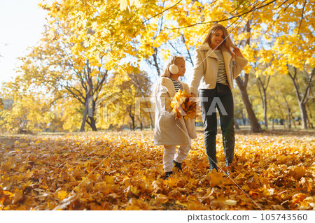 Happy mother and daughter have fun in autumn park at sunset. Family on walk. Childhood, walks, rest. 105743560