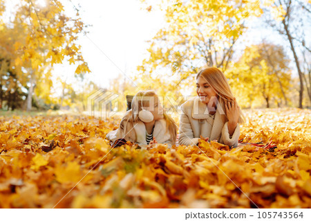 Happy mother and daughter have fun in autumn park at sunset. Family on walk. Childhood, walks, rest. 105743564