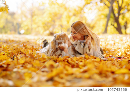 Happy mother and daughter have fun in autumn park at sunset. Family on walk. Childhood, walks, rest. Happy mother and daughter have fun in autumn park at sunset. Family on walk. Childhood, walks, rest. 105743566