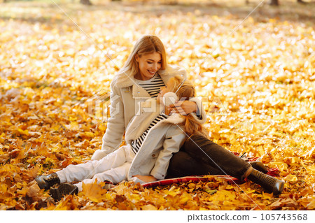 Happy mother and daughter have fun in autumn park at sunset. Family on walk. Childhood, walks, rest. 105743568