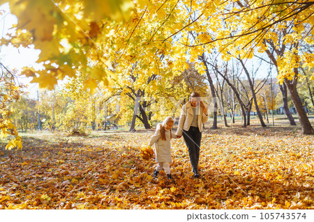 Happy mother and daughter have fun in autumn park at sunset. Family on walk. Childhood, walks, rest. 105743574