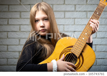 Beautiful blonde girl plays the guitar close up 105743781