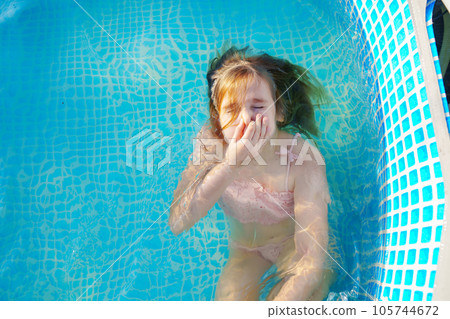 Cute teenage girl in pink swimsuit playing in a small pool. Cute teenage girl in pink swimsuit playing in a small pool. 105744672