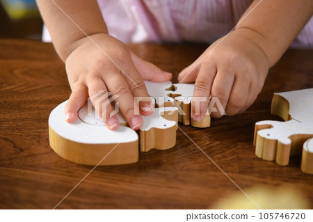 Little girl playing with woodworking jigsaw puzzle Little girl playing with woodworking jigsaw puzzle 105746720