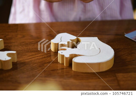 Little girl playing with woodworking jigsaw puzzle Little girl playing with woodworking jigsaw puzzle 105746721