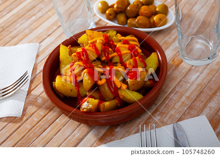Top view of Patatas bravas, Spanish dish of fried potatoes served with cheese sauce and spicy sauce with paprika 105748260