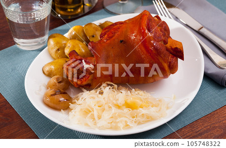 Oven baked pork knuckle with potatoes and cabbage on plate Oven baked pork knuckle with potatoes and cabbage on plate 105748322