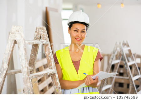 Positive woman builder with documents during repair works Positive woman builder with documents during repair works 105748589