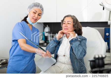 Smiling aged woman looking at mirror after hardware facial procedure Smiling aged woman looking at mirror after hardware facial procedure 105748605