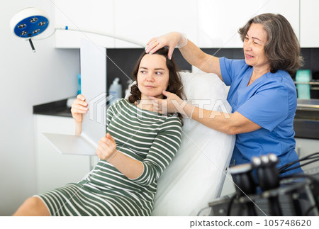 Experienced cosmetology doctor examines face a young woman patient 105748620