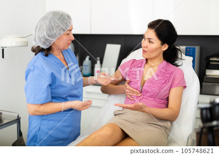 Experienced cosmetology doctor tells a young female patient about the health of the female breast 105748621