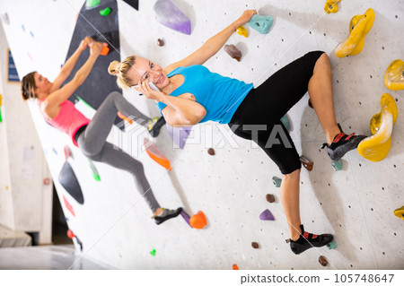 Woman having phone call during training in bouldering gym 105748647