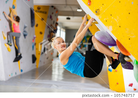 Woman exercising in climbing gym Woman exercising in climbing gym 105748757
