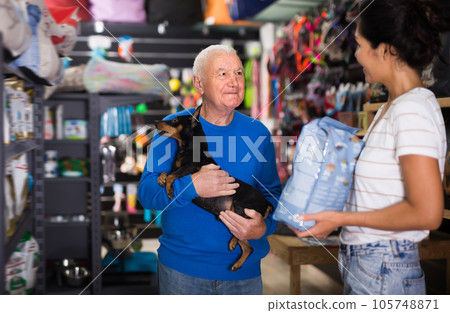 Saleswoman consulting old man about dog food in pet shop Saleswoman consulting old man about dog food in pet shop 105748871
