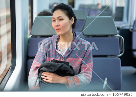 Portrait of a woman traveler with a backpack and a phone in train car 105749025
