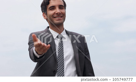 Modern businessman smiles and stretches his hand to the camera wishing to greet 105749777