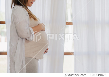 pregnancy woman hugging her tummy and feel happy with big belly at window pregnancy woman hugging her tummy and feel happy with big belly at window 105749828