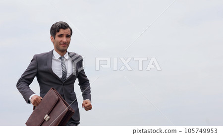 Studio shot of a mature businessman running with a briefcase isolated against the sky. 105749953