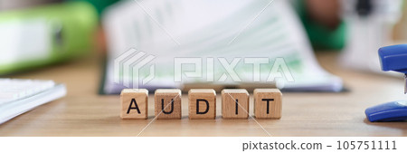 Word audit collected from wooden cubes and auditor working with documents in background. Word audit collected from wooden cubes and auditor working with documents in background. 105751111