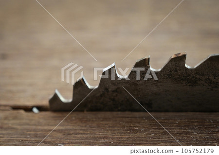 sharp metal saw on wood plank texture background, construction machine 105752179