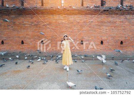 Young asian woman traveler in Yellow dress with hat and bag traveling on Tha Pae Gate, Tourist visit at the old city in Chang Mai, Thailand. Asia Travel, Vacation and summer holiday concept Young asian woman traveler in Yellow dress with hat and bag traveling on Tha Pae Gate, Tourist visit at the old city in Chang Mai, Thailand. Asia Travel, Vacation and summer holiday concept 105752792