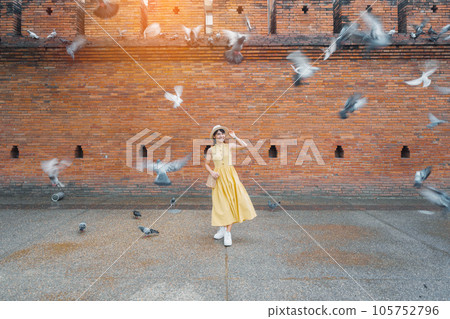 Young asian woman traveler in Yellow dress with hat and bag traveling on Tha Pae Gate, Tourist visit at the old city in Chang Mai, Thailand. Asia Travel, Vacation and summer holiday concept 105752796