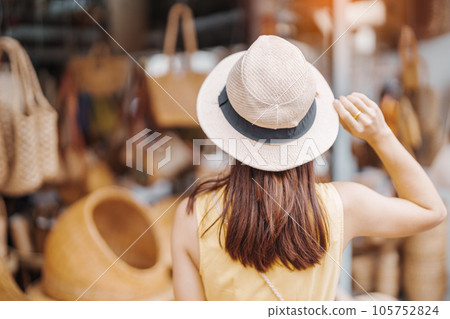 Young asian woman traveler in dress with hat traveling to wicker shop on Chang Moi Kao Road, Tourist visit at the old city in Chang Mai, Thailand. Asia Travel, Vacation and summer holiday concept Young asian woman traveler in dress with hat traveling to wicker shop on Chang Moi Kao Road, Tourist visit at the old city in Chang Mai, Thailand. Asia Travel, Vacation and summer holiday concept 105752824