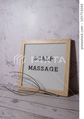 Scalp massager for home with letter board SCALP MASSAGE text. Close up of scalp massaging brush for hair growing routine. Anti stress acupuncture metal octopus tool equipment. Manual device for home Scalp massager for home with letter board SCALP MASSAGE text. Close up of scalp massaging brush for hair growing routine. Anti stress acupuncture metal octopus tool equipment. Manual device for home 105753048