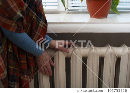 Caucasian female warming up hands near Hot Water Radiator. Caucasian female warming up hands near Hot Water Radiator. 105753526