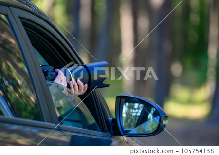 A private detective is sitting in the car, filming. The paparazzi sits in the car and photographs a famous person. Spy with a camera in the car. A private detective is sitting in the car, filming. The paparazzi sits in the car and photographs a famous person. Spy with a camera in the car. 105754138