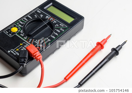 Digital multimeter with test leads on a white table. A multimeter is an electronic measuring instrument. Digital multimeter with test leads on a white table. A multimeter is an electronic measuring instrument. 105754146