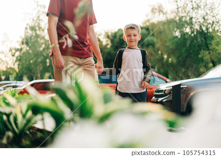 Happy father and kid son going to classes. Parent take child boy to school in first grade. Pupil of primary school go study with backpack outdoors in city street. Beginning of lessons. Back to school Happy father and kid son going to classes. Parent take child boy to school in first grade. Pupil of primary school go study with backpack outdoors in city street. Beginning of lessons. Back to school 105754315
