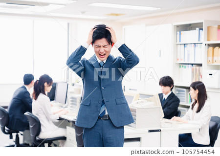 Young businessman holding his head in the office Young businessman holding his head in the office 105754454