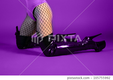 Sexy female legs in high heel shoes and fishnet stockings on purple background Sexy female legs in high heel shoes and fishnet stockings on purple background 105755992