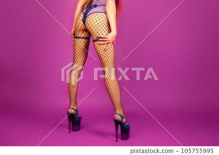 Sexy female legs in high heel shoes and fishnet stockings on pink background Sexy female legs in high heel shoes and fishnet stockings on pink background 105755995