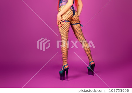 Sexy female legs in high heel shoes and fishnet stockings on pink background Sexy female legs in high heel shoes and fishnet stockings on pink background 105755996