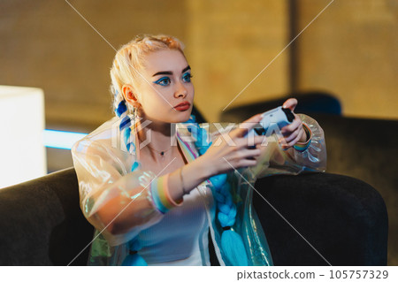 Portrait of a young female gamer playing console. 105757329